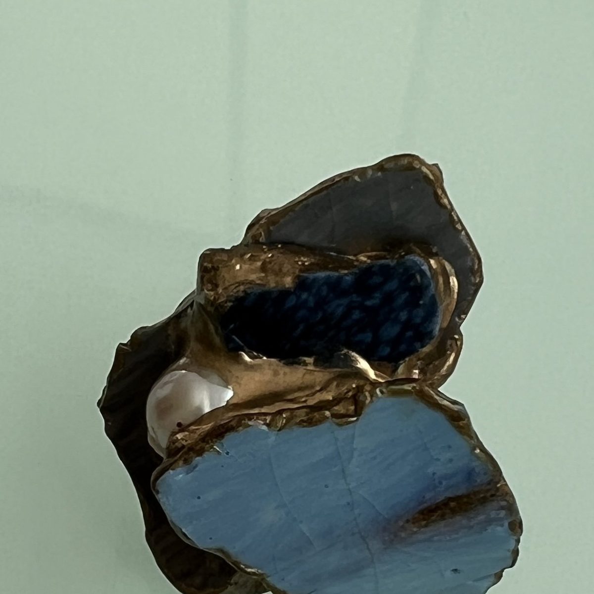 Ring of pale blue ceramic joined with a gold seam and set with a pearl.